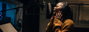 Black female singer singing into microphone in recording studio